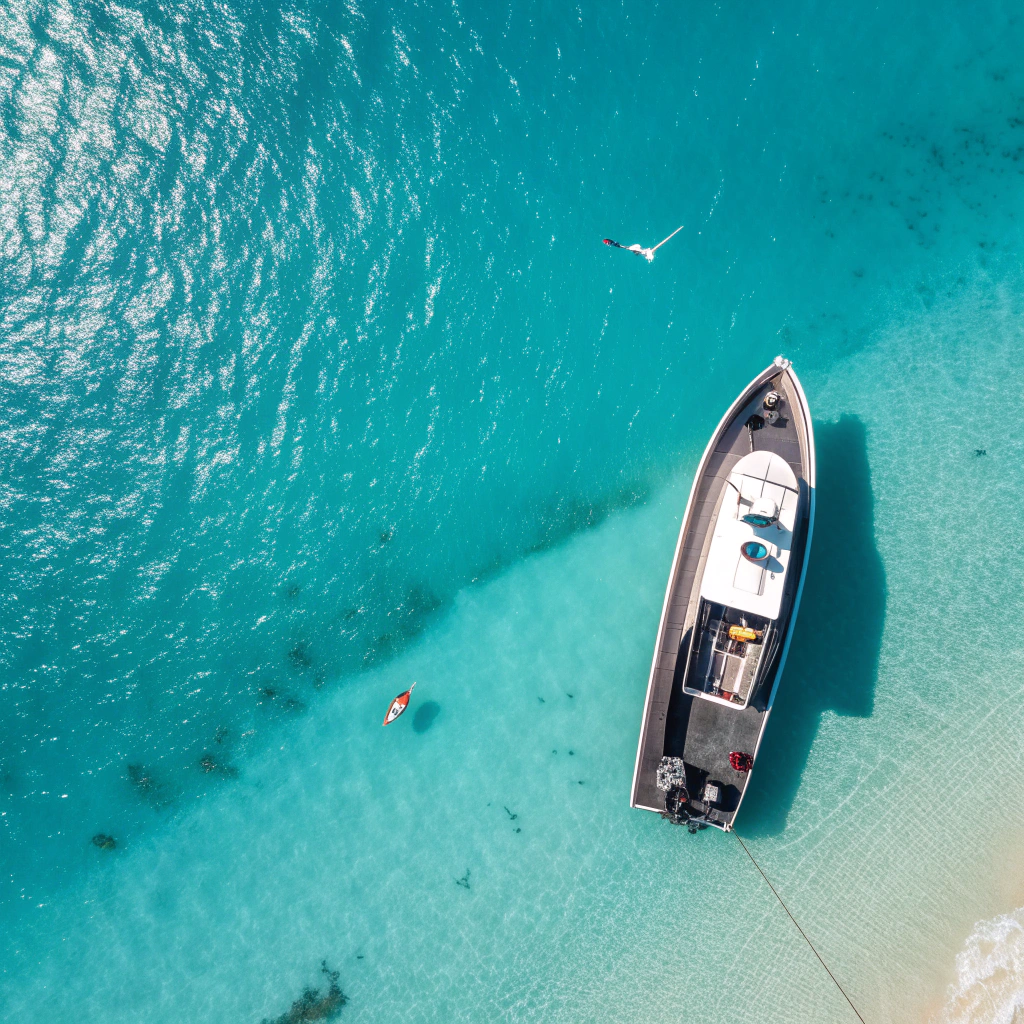 Vista aerea di una barca open boat che attraversa acque turchesi tra Cala Jond
